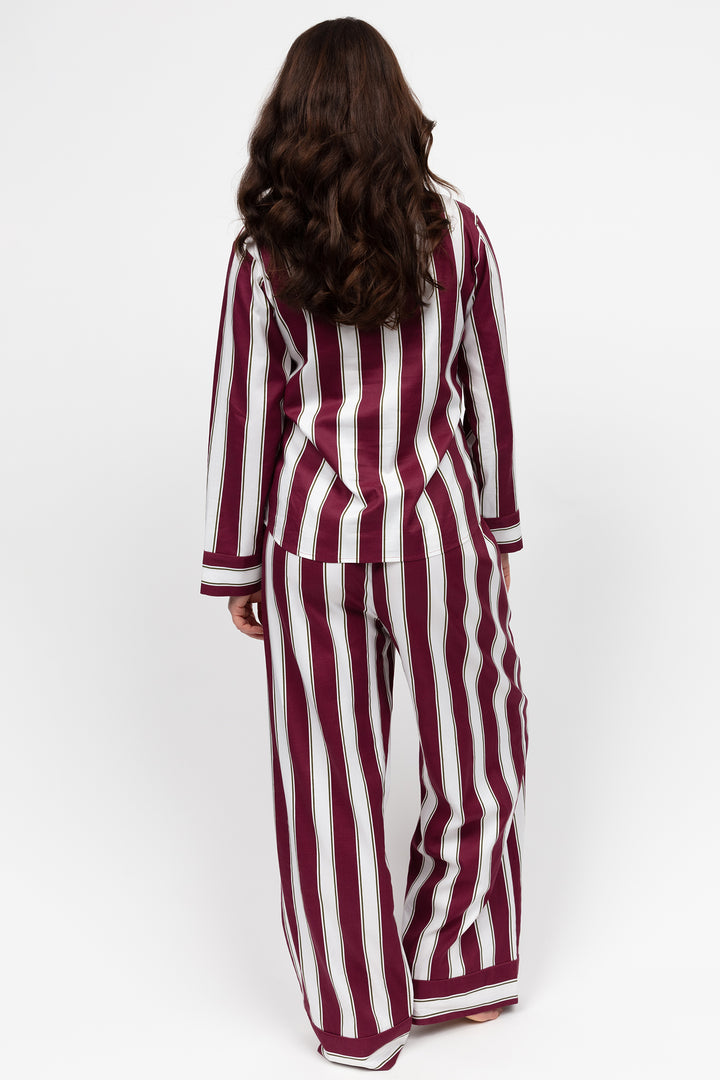 Woman wearing a burgundy and white striped pajama set on a white background