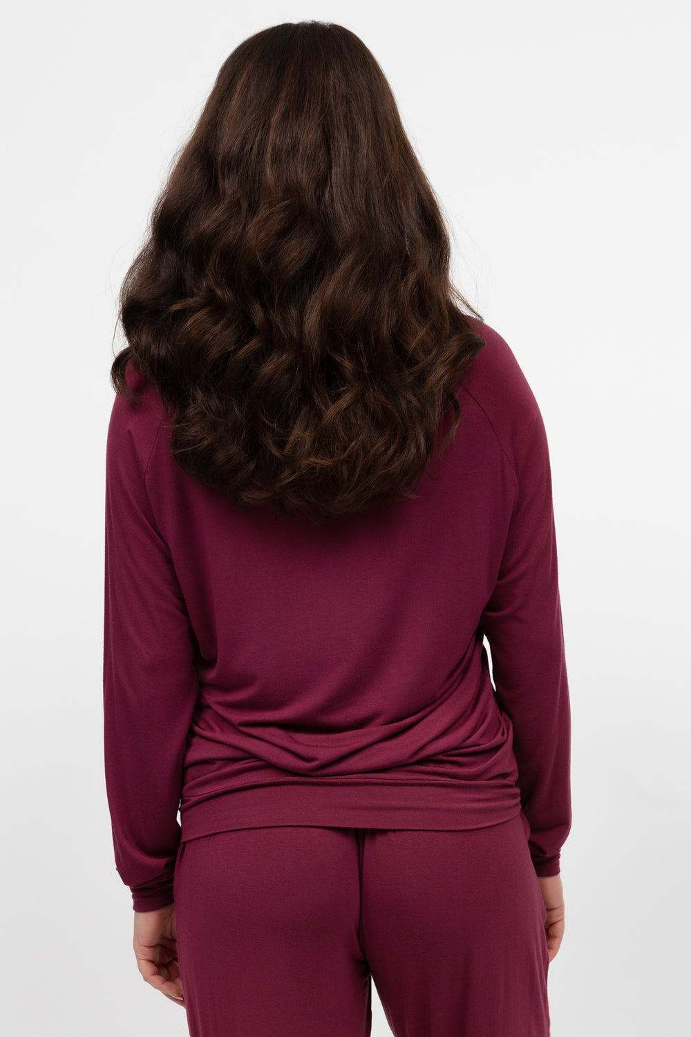 Person wearing a burgundy long-sleeve top and pants on a white background