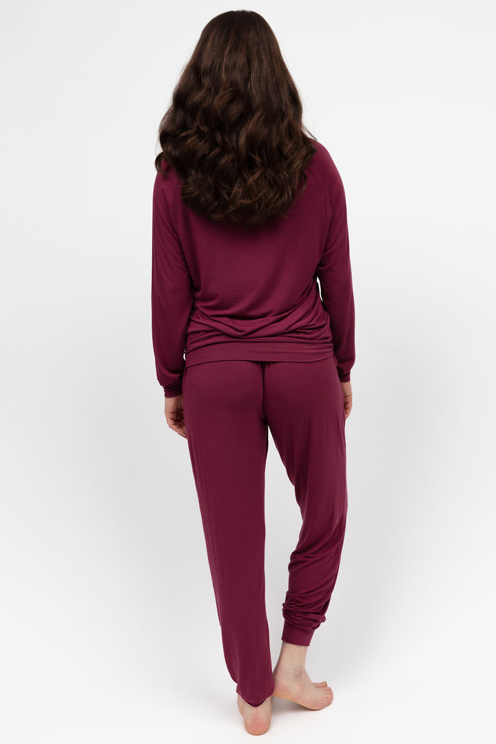 Person wearing a burgundy loungewear set on a white background