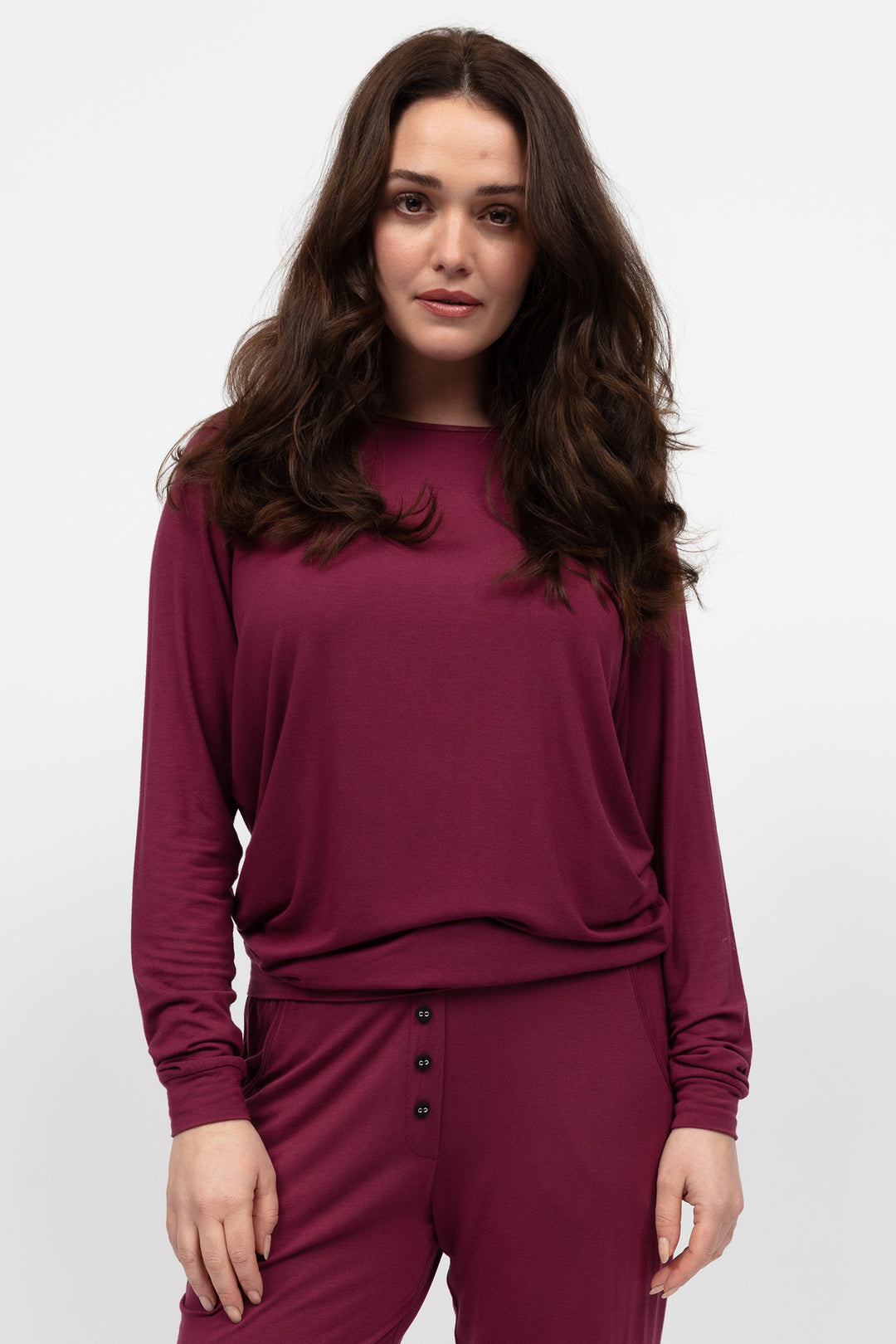 Woman wearing a burgundy outfit with a plain background