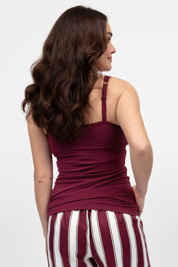 Woman wearing a burgundy top and striped pants on a white background