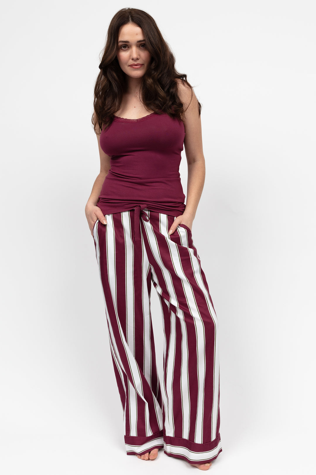 Woman wearing a purple top and wide-leg striped pants on a white background