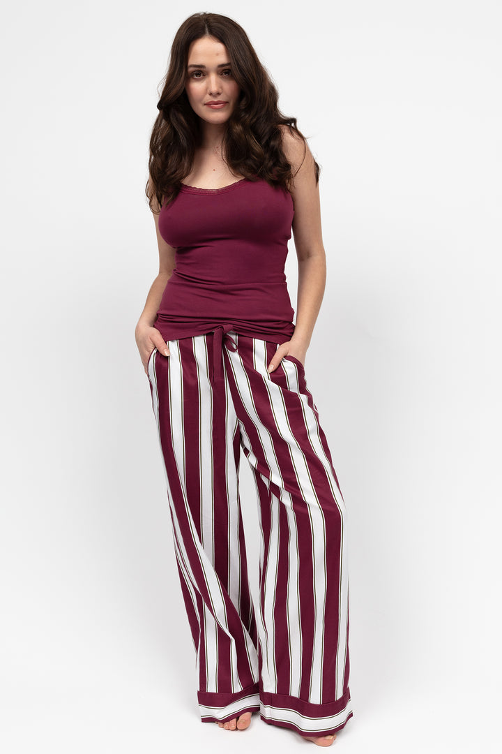 Woman wearing a purple top and wide-leg striped pants on a white background