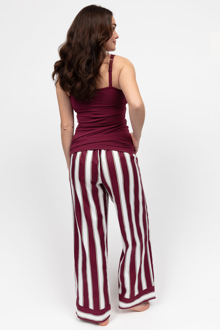 Woman wearing a burgundy tank top and striped pants on a white background