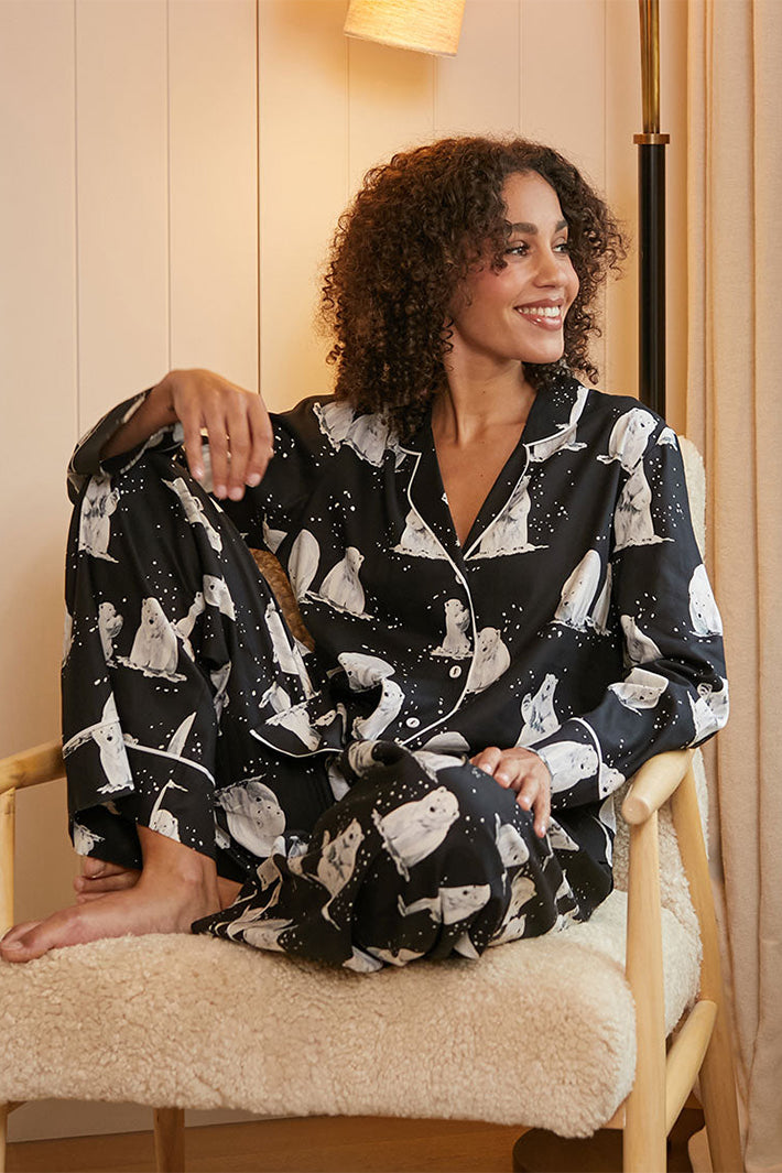 Cyberjammies Polar Drift Polar Bear Print Black Long Sleeve Pyjama Top, worn sitting in a chair