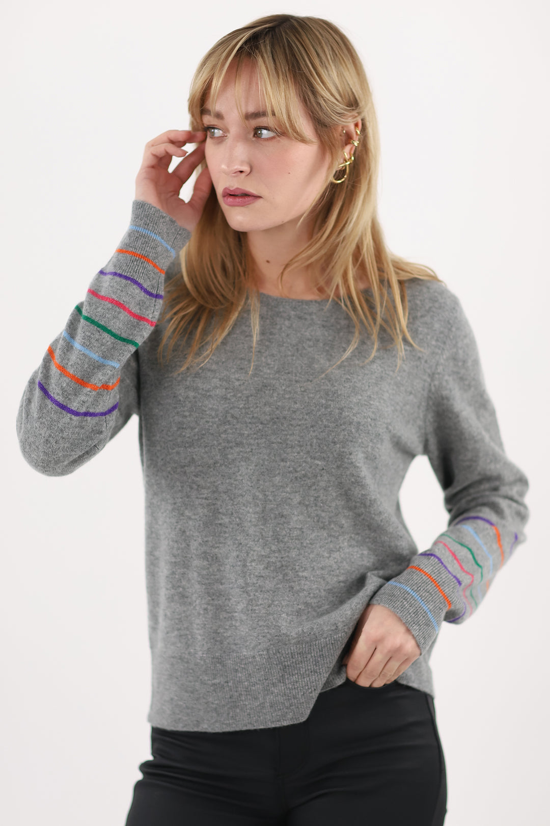 Woman wearing a gray sweater with colorful sleeves on a white background