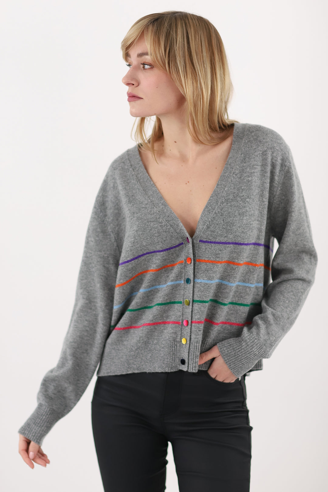 Woman wearing a gray cardigan with colorful stripes on a white background
