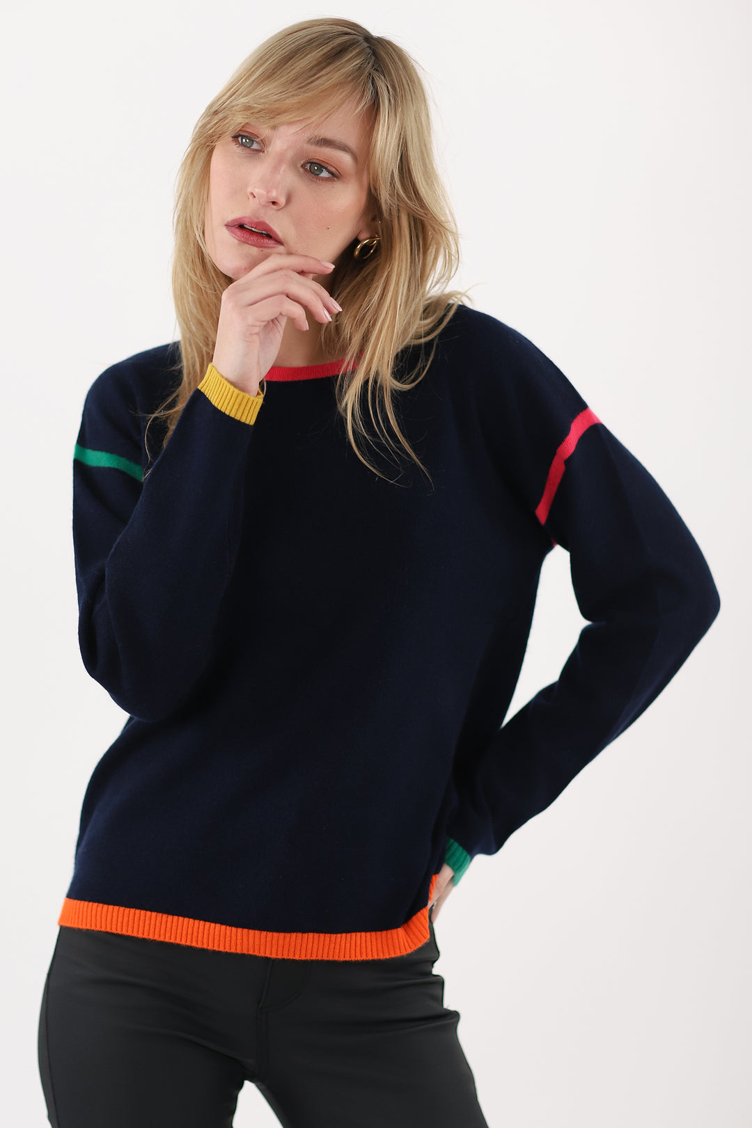 Woman wearing a navy sweater with colorful stripes on a white background