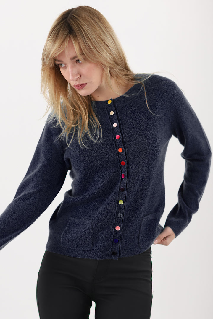 Woman wearing a navy cardigan with colorful buttons on a white background