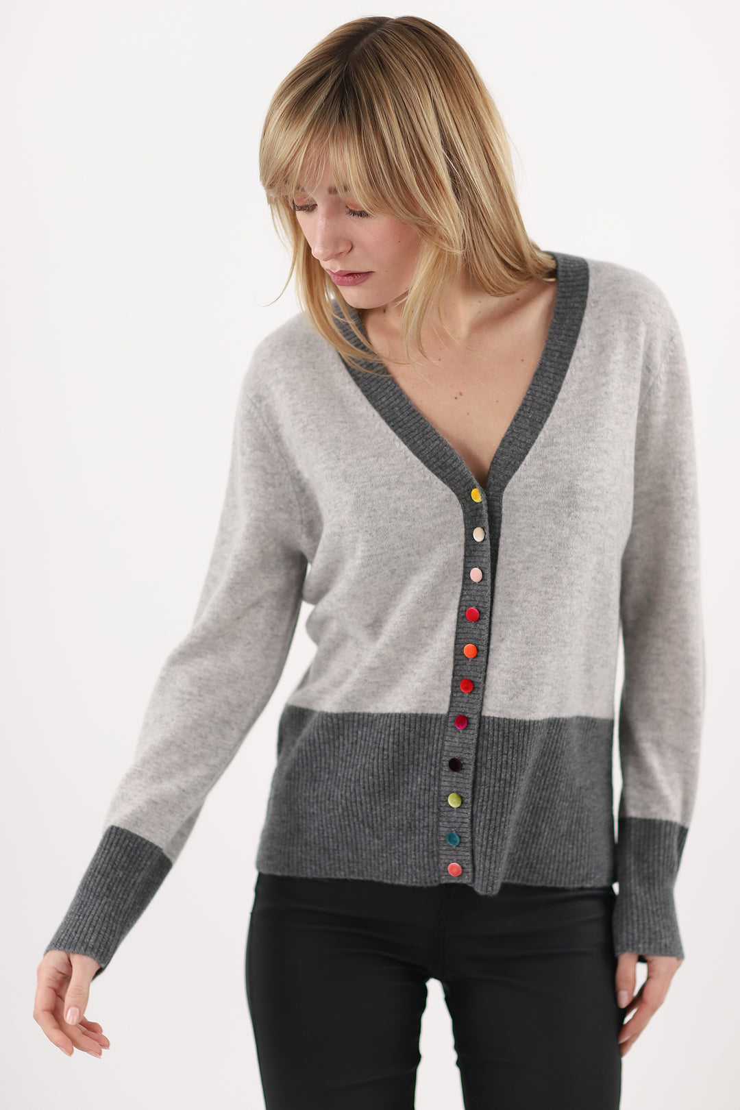 Woman wearing a gray cardigan with colorful buttons on a white background