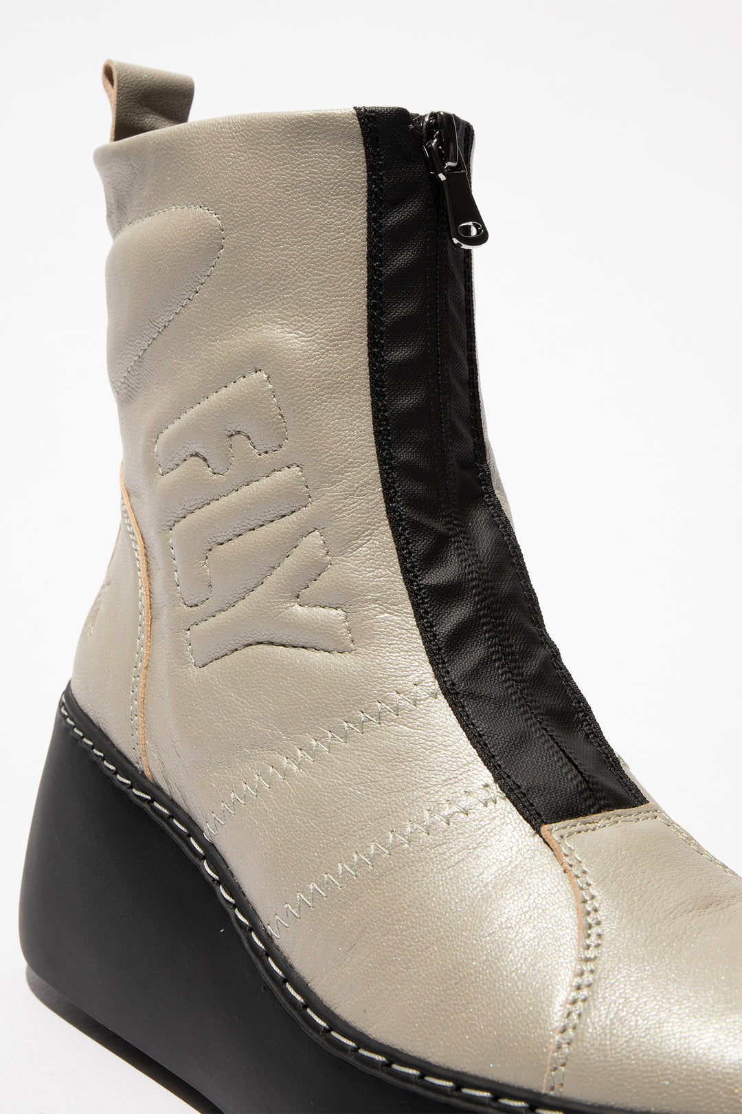 Close-up of a beige and black ankle boot with 'Fly' branding on a white background