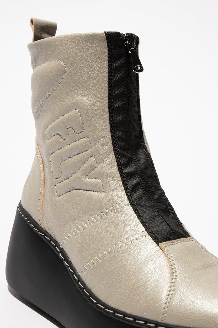 Close-up of a beige and black ankle boot with 'Fly' branding on a white background