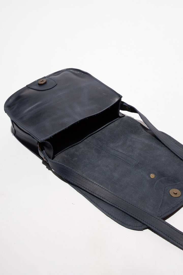 Dark blue leather bag with a strap on a white background