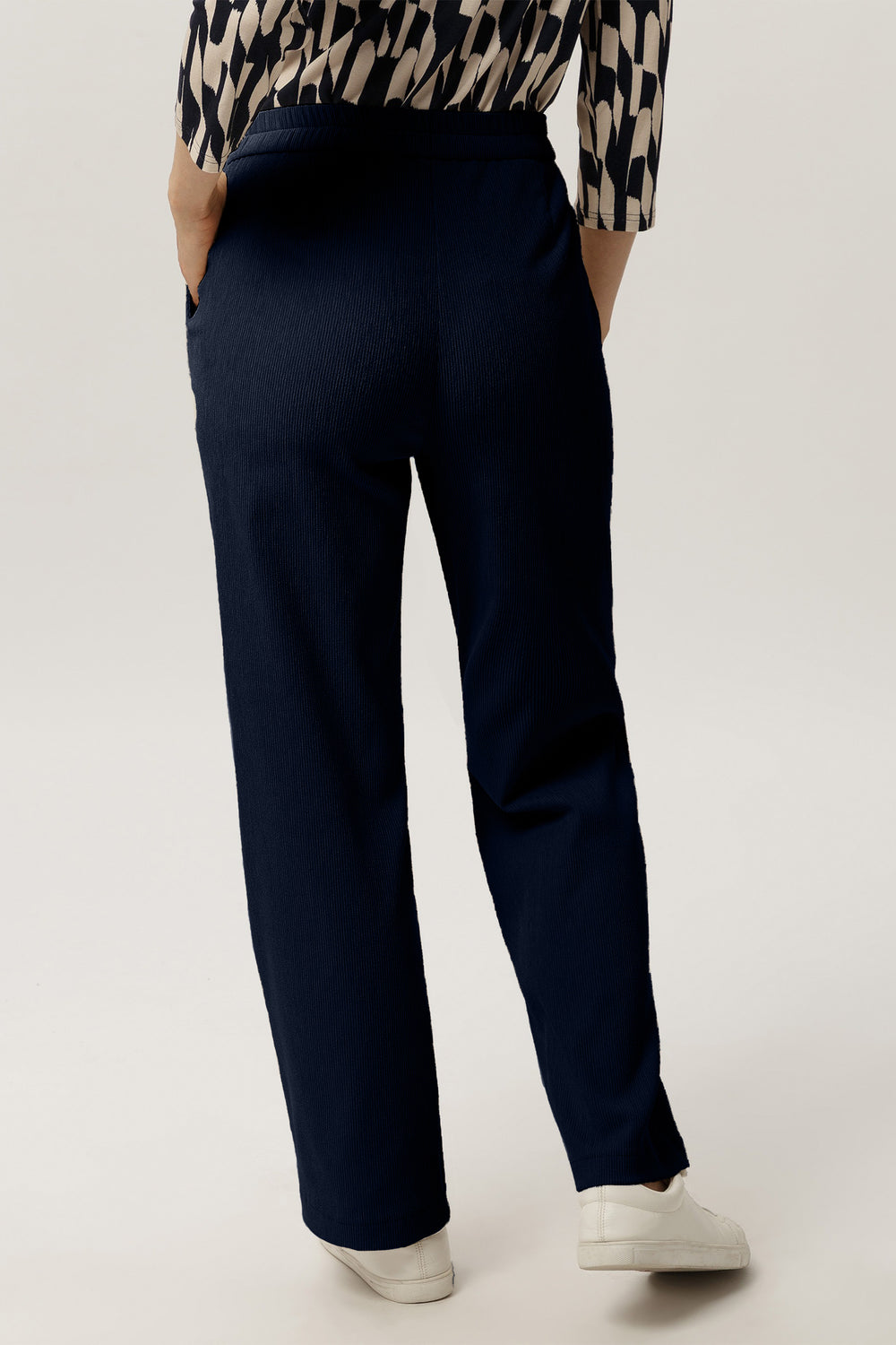 Navy blue pants worn by a person on a white background