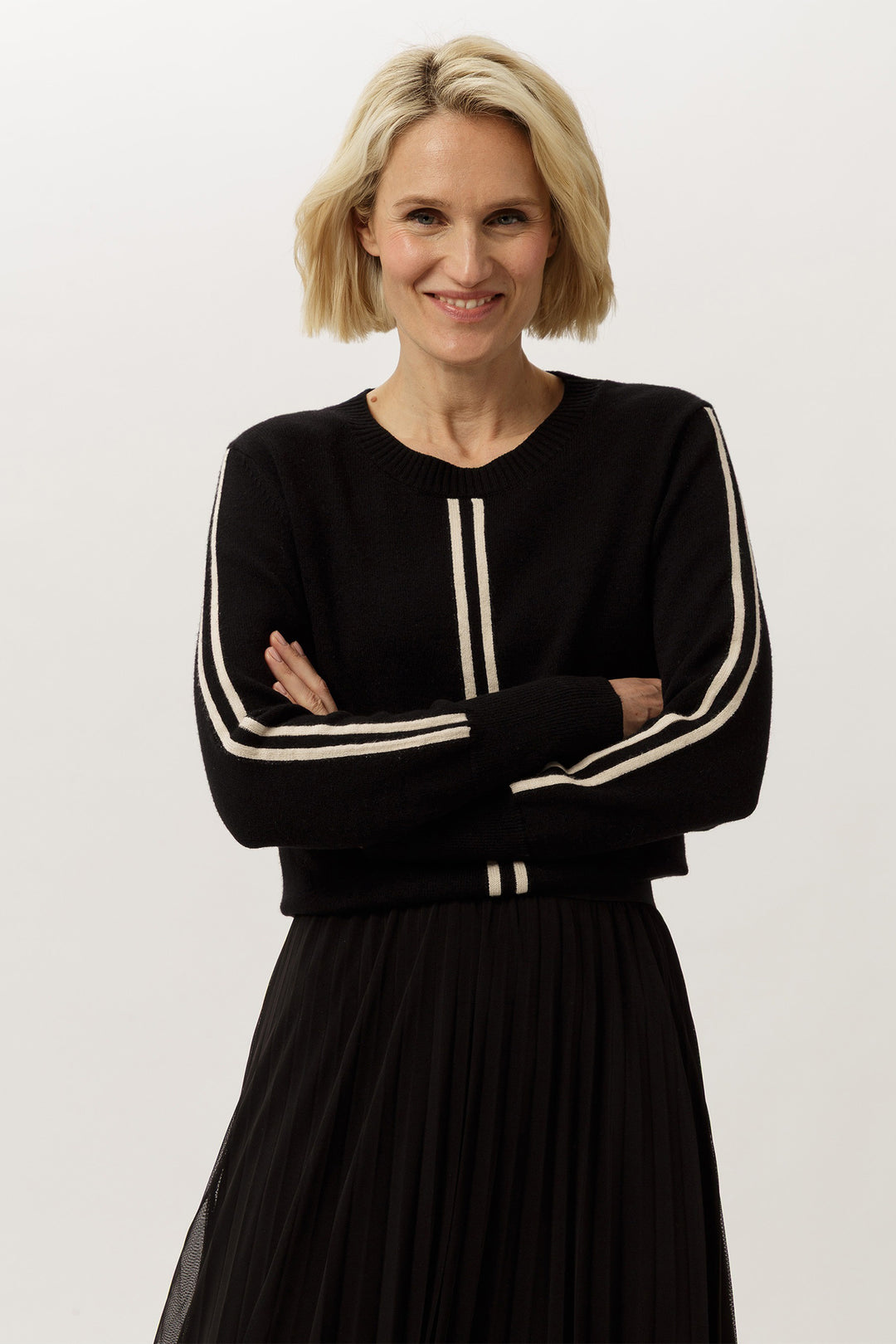 Woman wearing a black dress with white stripes on a plain background