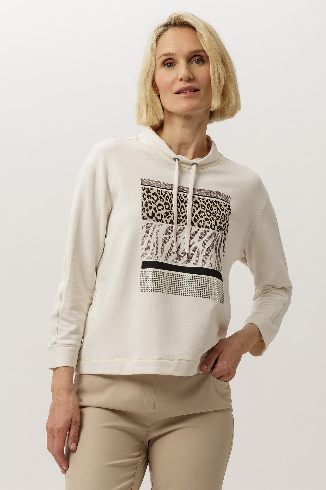Woman wearing a white hoodie with a patterned design on a plain background