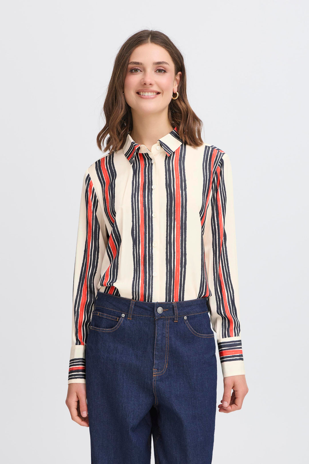 Woman wearing a striped shirt and blue jeans on a plain background