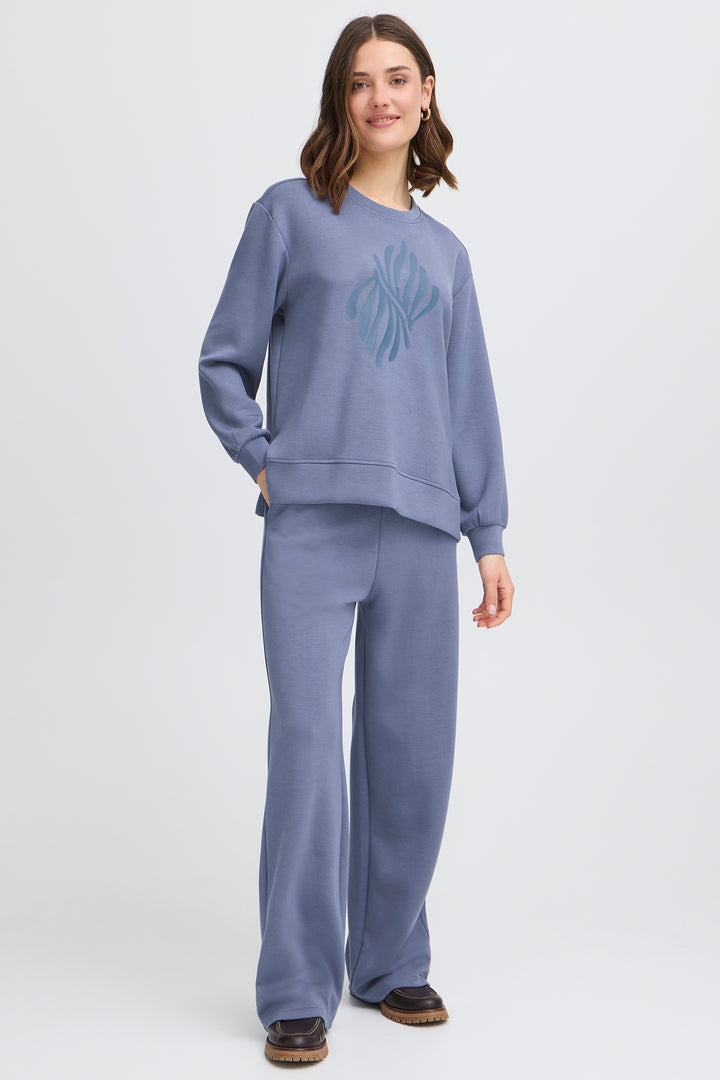 Woman wearing a blue sweatshirt and pants set on a white background