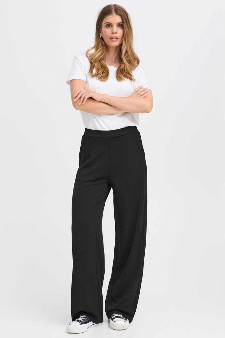 Woman wearing a white top and black wide-leg pants on a white background