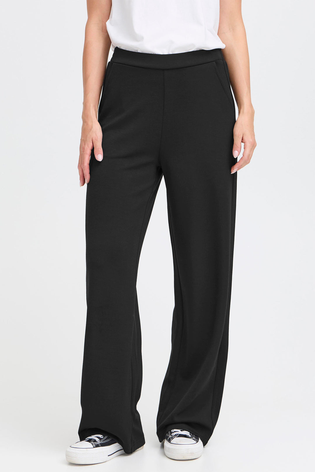 Person wearing black wide-leg pants on a white background