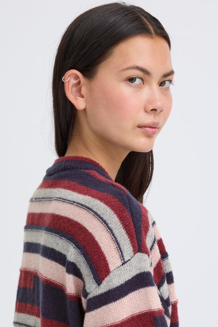 Woman wearing a colorful striped sweater against a plain background