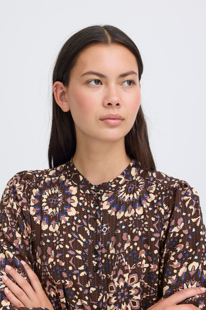 Woman wearing a patterned blouse against a plain background