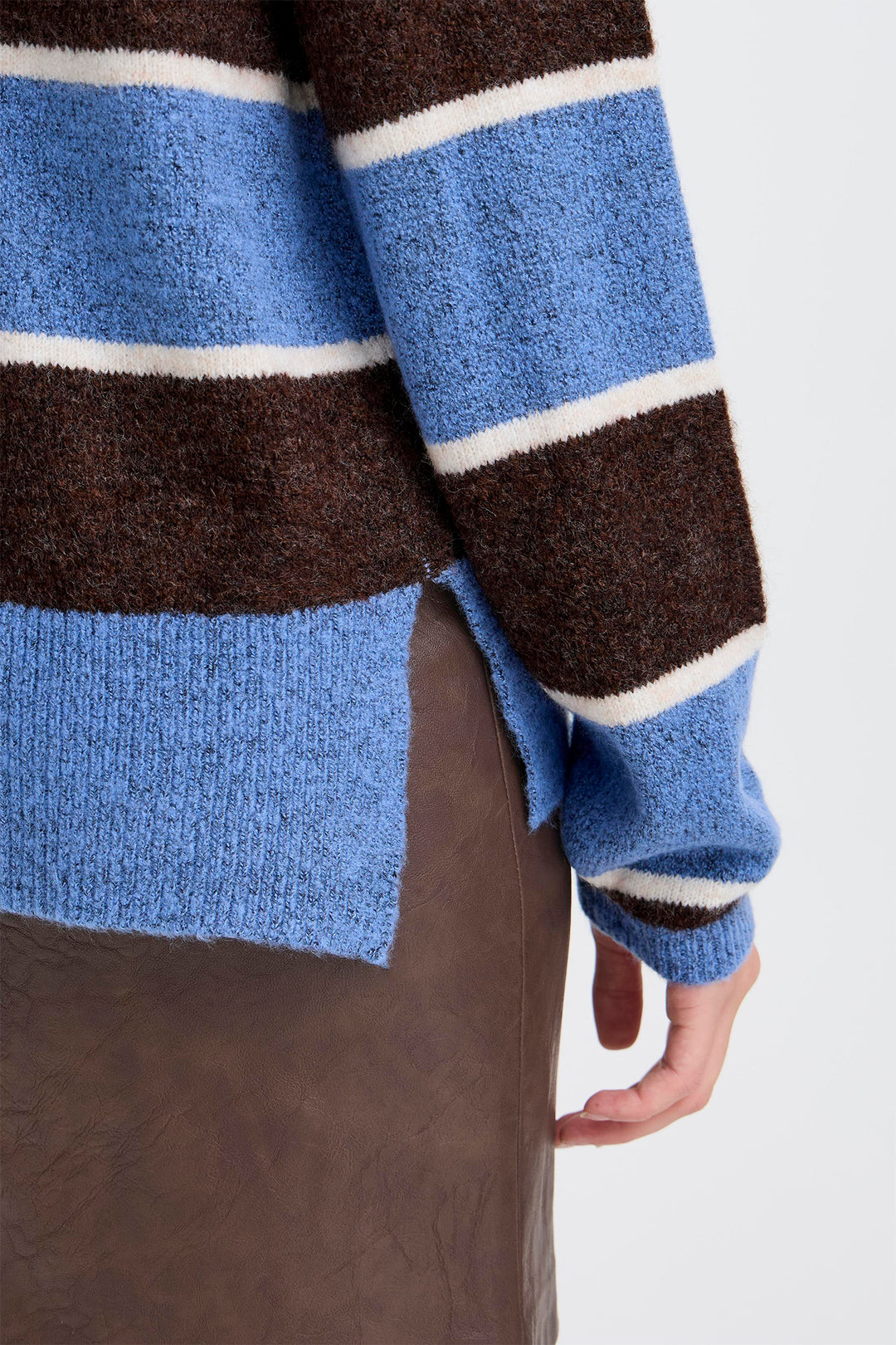 Close-up of a sweater with blue, brown, and white stripes on a plain background
