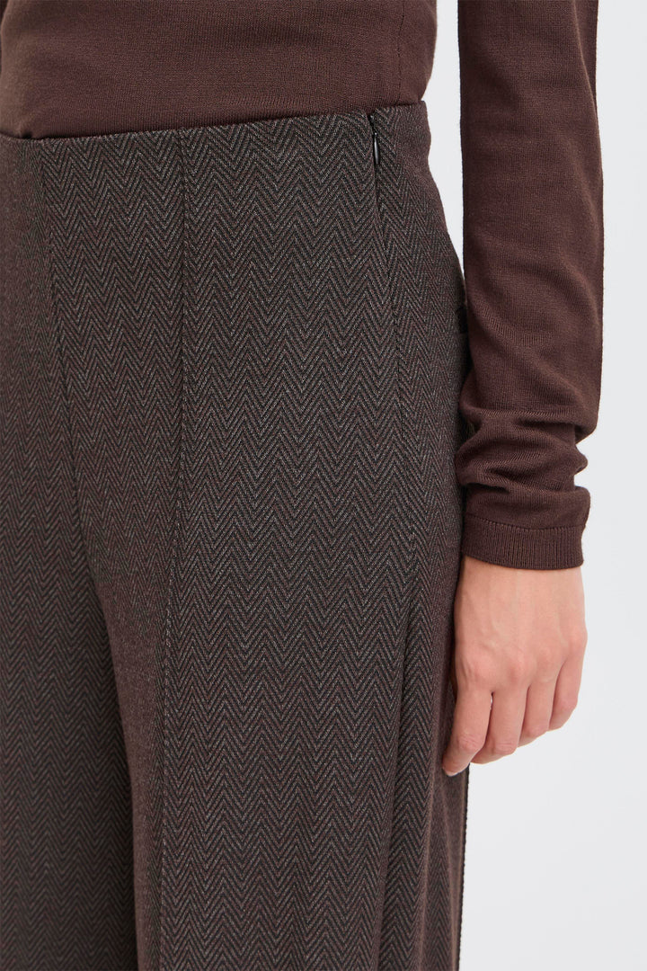 Brown herringbone patterned pants worn by a person on a white background