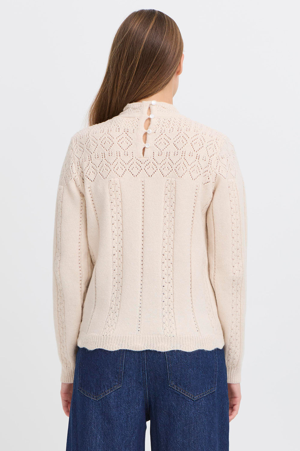 Woman wearing a beige knitted cardigan with a white background