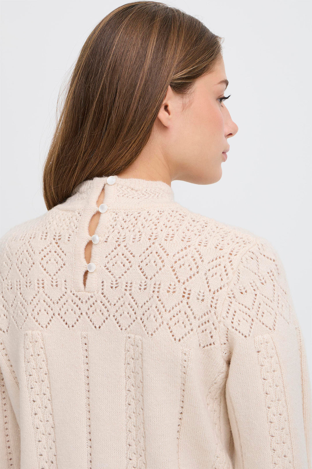 Woman wearing a beige knitted cardigan against a white background