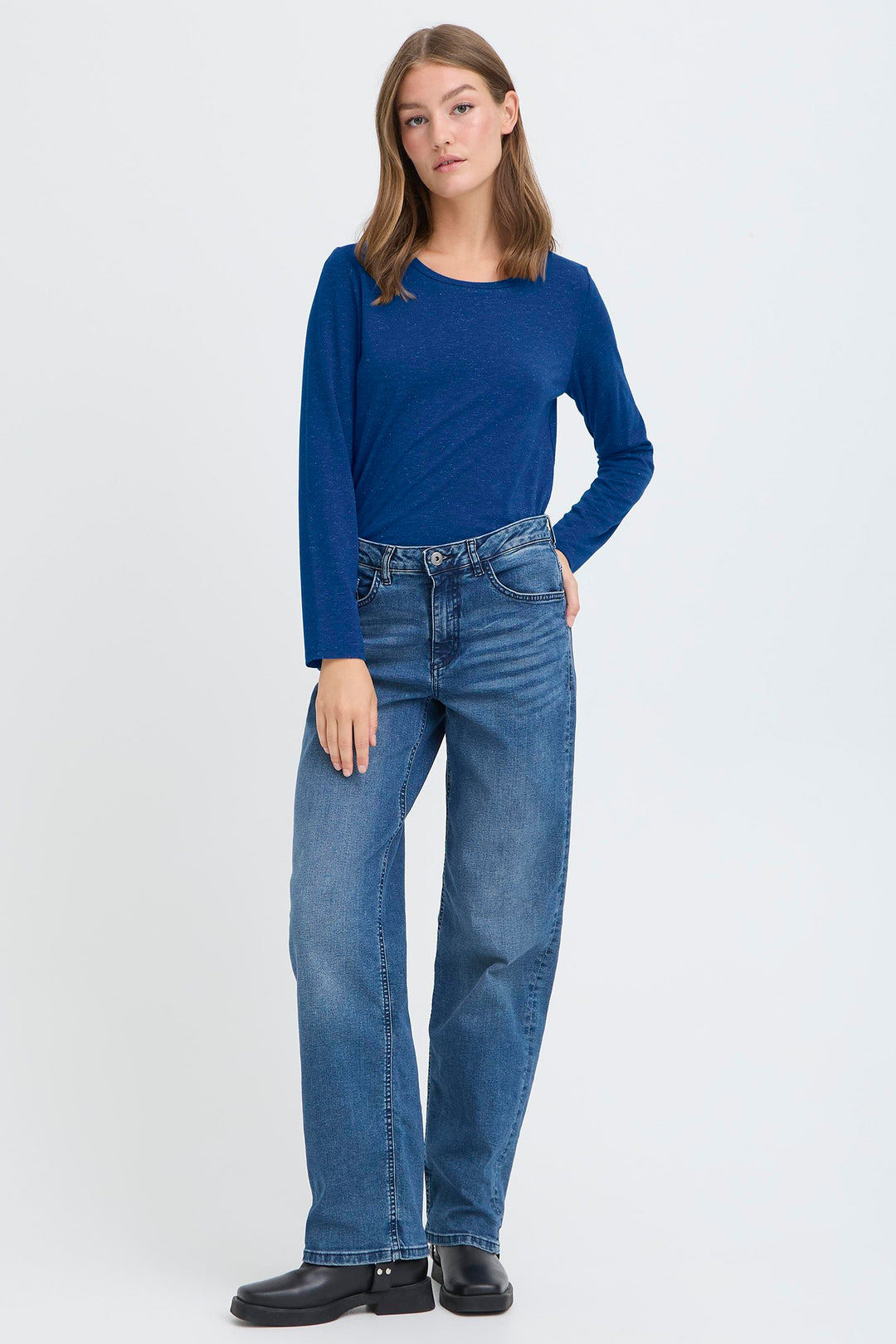 Woman wearing a blue sweater and jeans on a white background