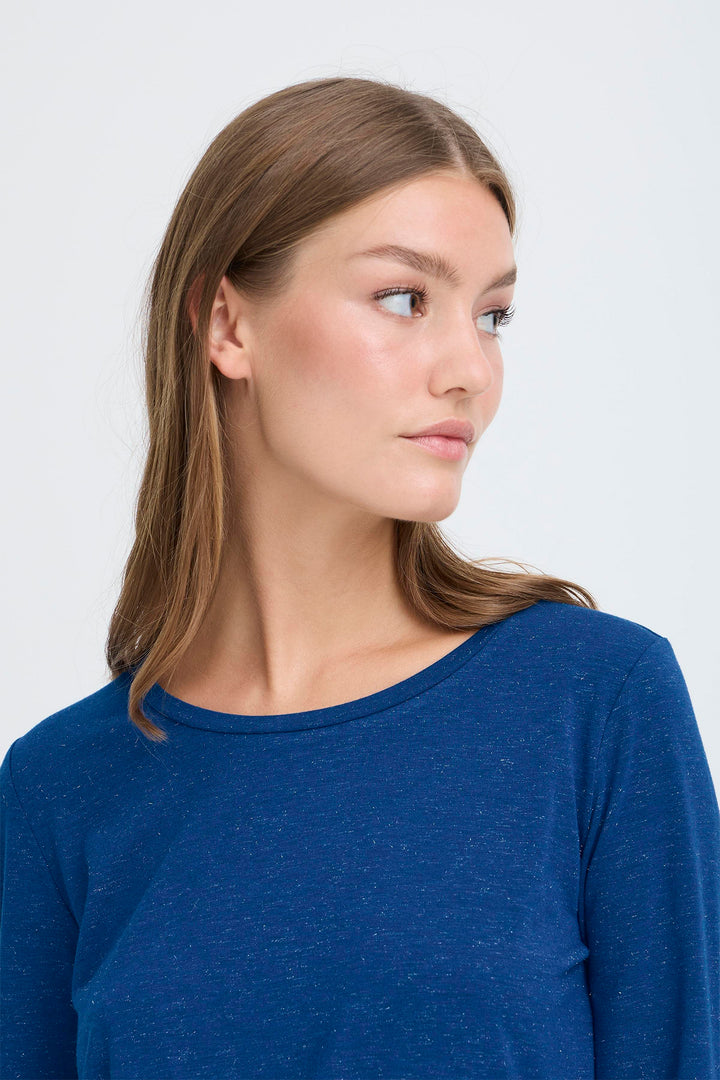 Woman wearing a blue long-sleeve shirt against a white background