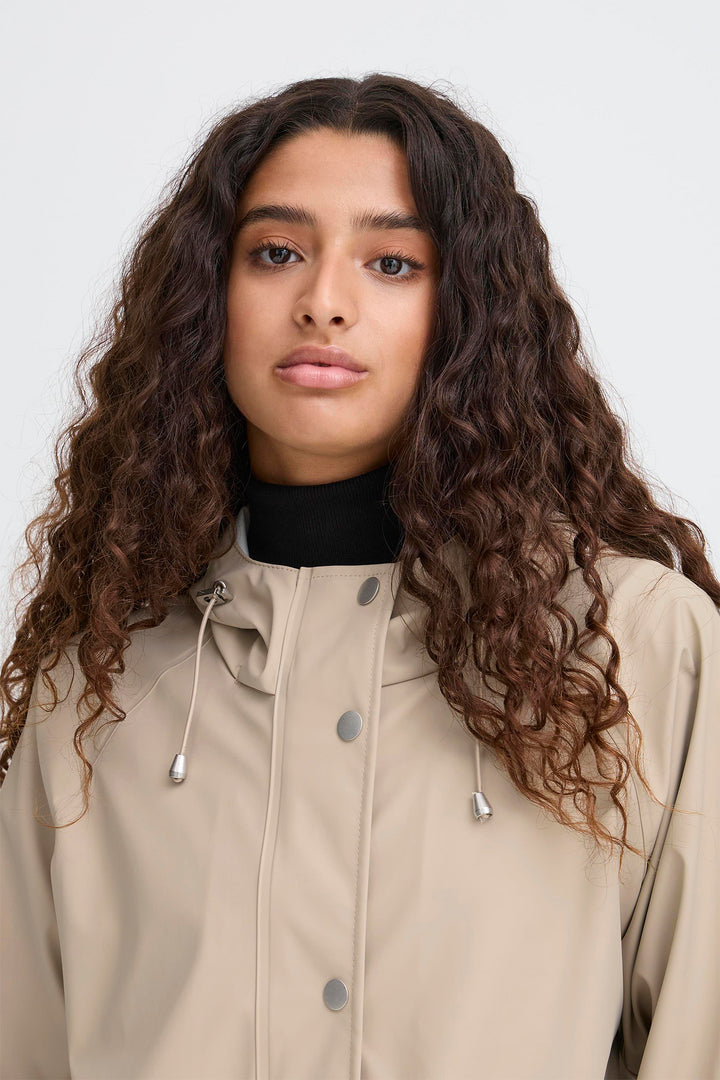Woman wearing a beige jacket with a plain background