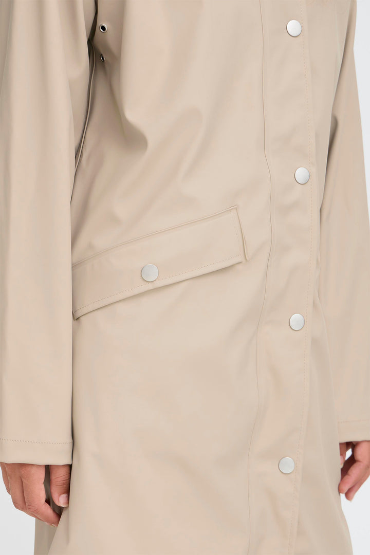 Beige trench coat with button details on a white background