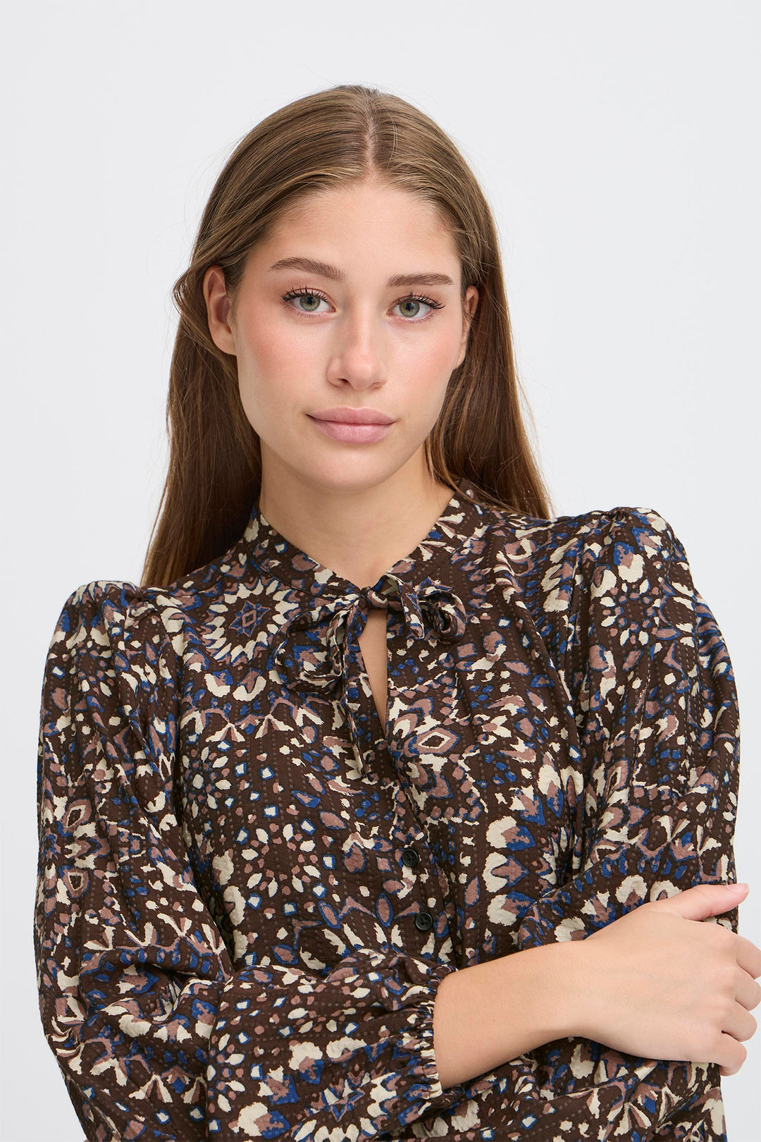 Woman wearing a patterned blouse against a plain background
