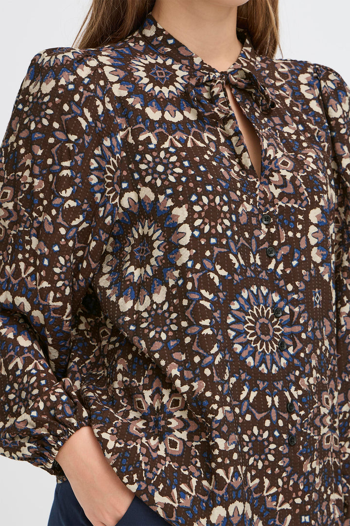 Close-up of a patterned blouse with intricate designs on a plain background