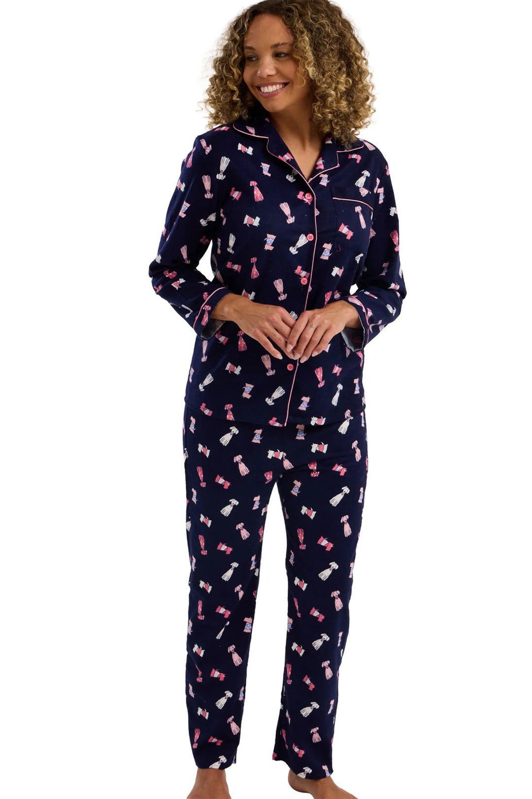 Woman wearing navy pajamas with pink dog patterns on a white background