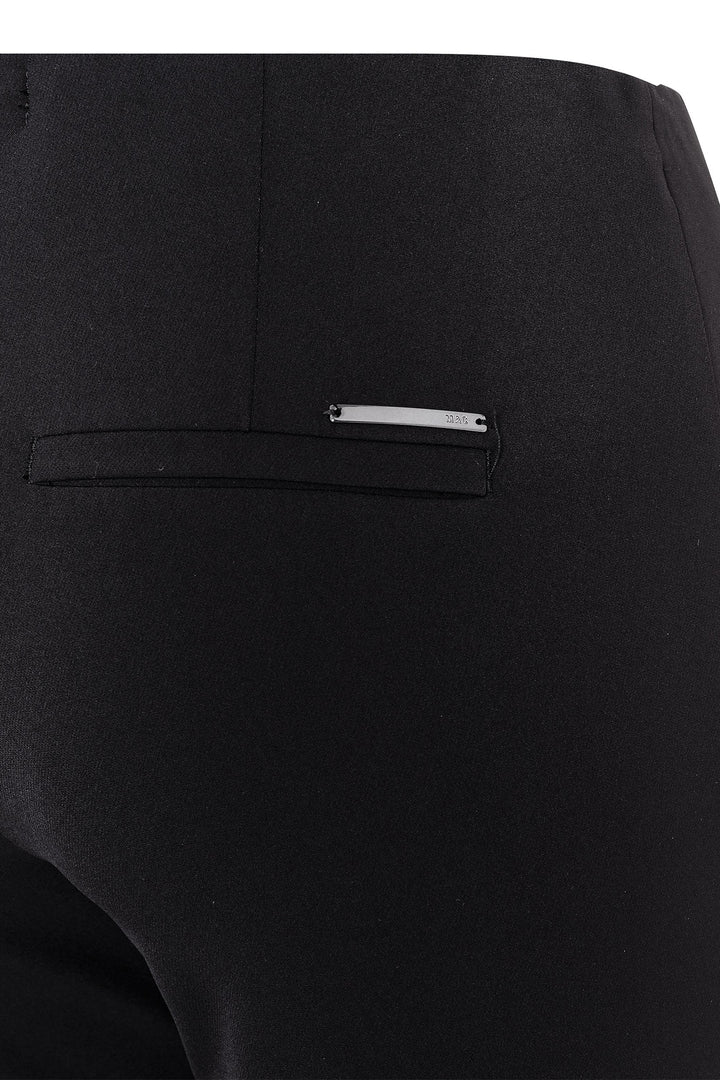 Close-up of a black pocket with a small metallic tag on a black background