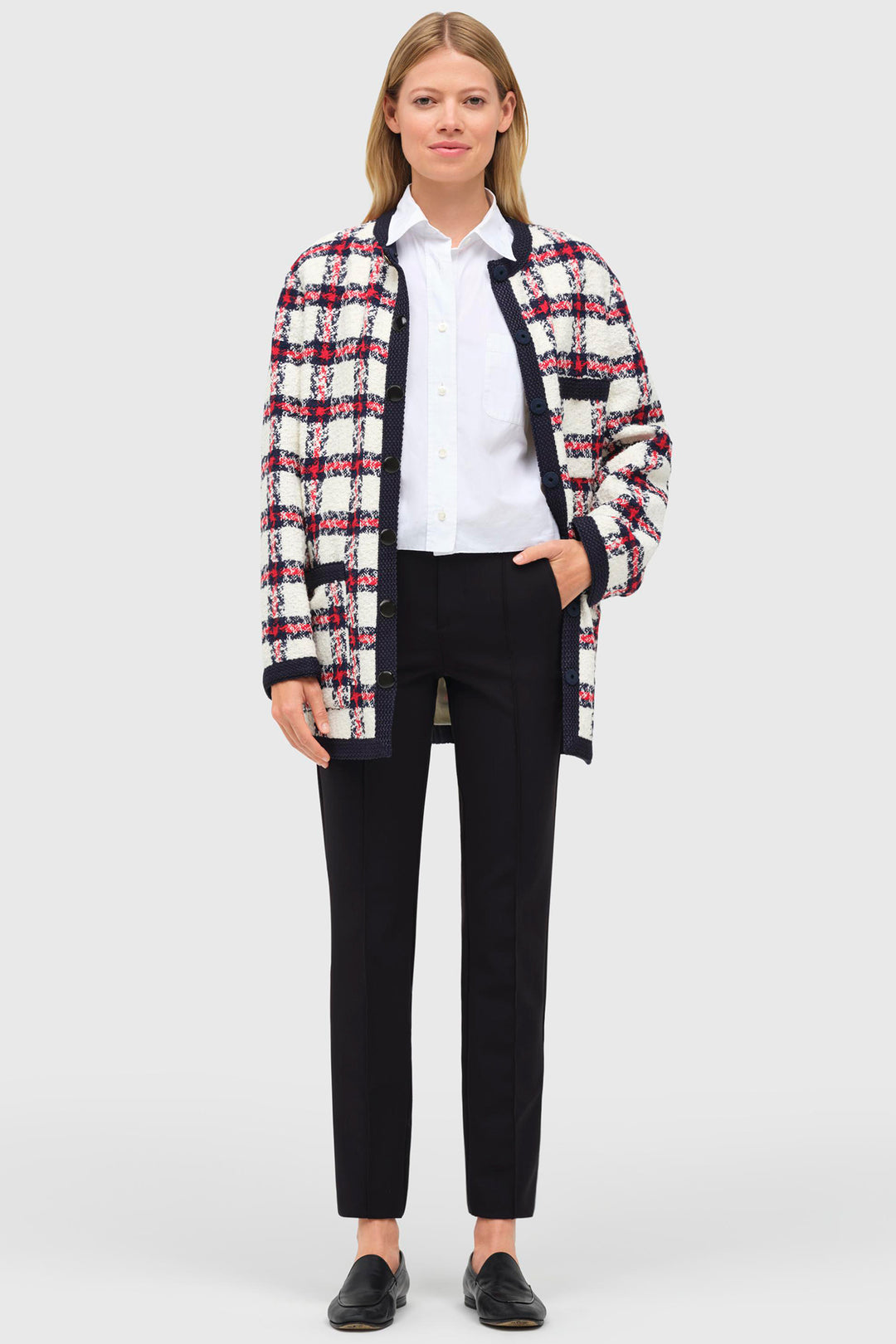 Woman wearing a plaid jacket over a white shirt and black pants on a white background