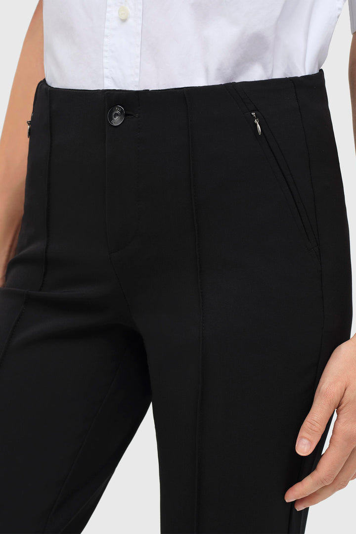 Black pants worn with a white shirt on a plain background