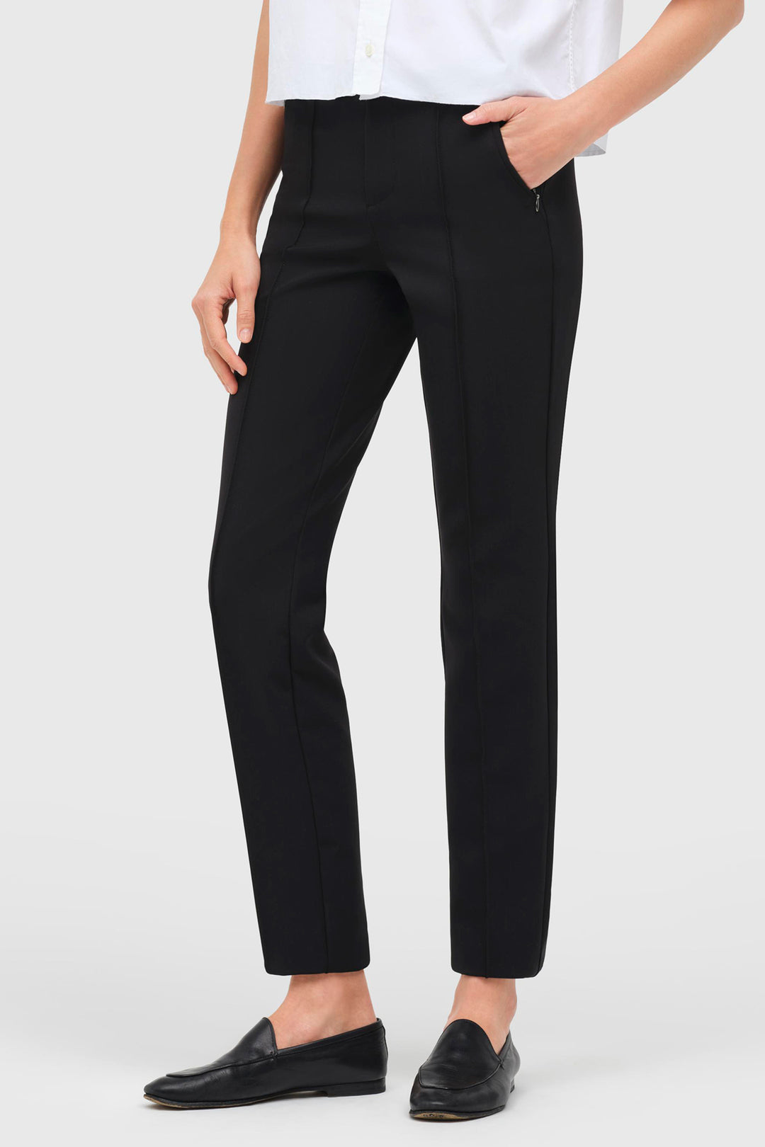 Person wearing black pants and a white shirt on a plain background