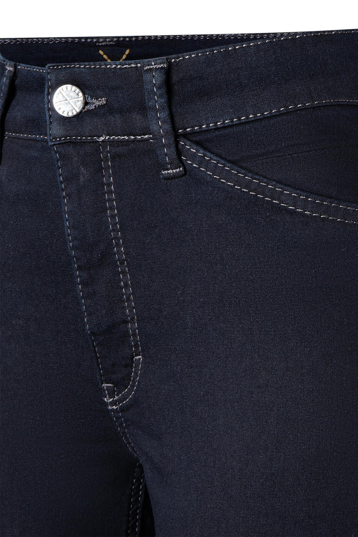 Close-up of dark blue jeans with a button and stitching detail.