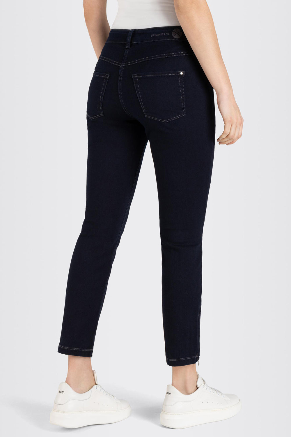 Person wearing dark blue jeans on a white background