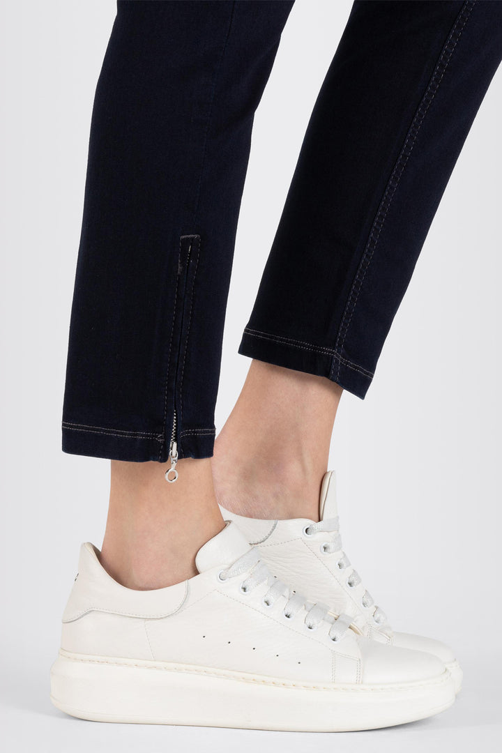 White sneakers worn with black pants on a white background