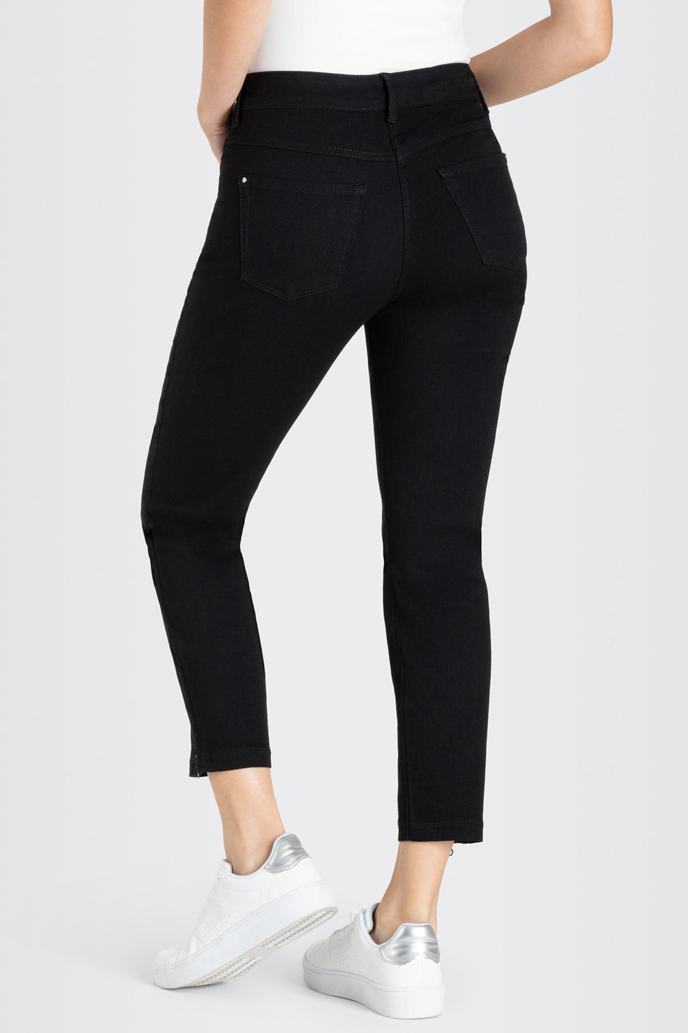 Person wearing black jeans and white sneakers on a white background