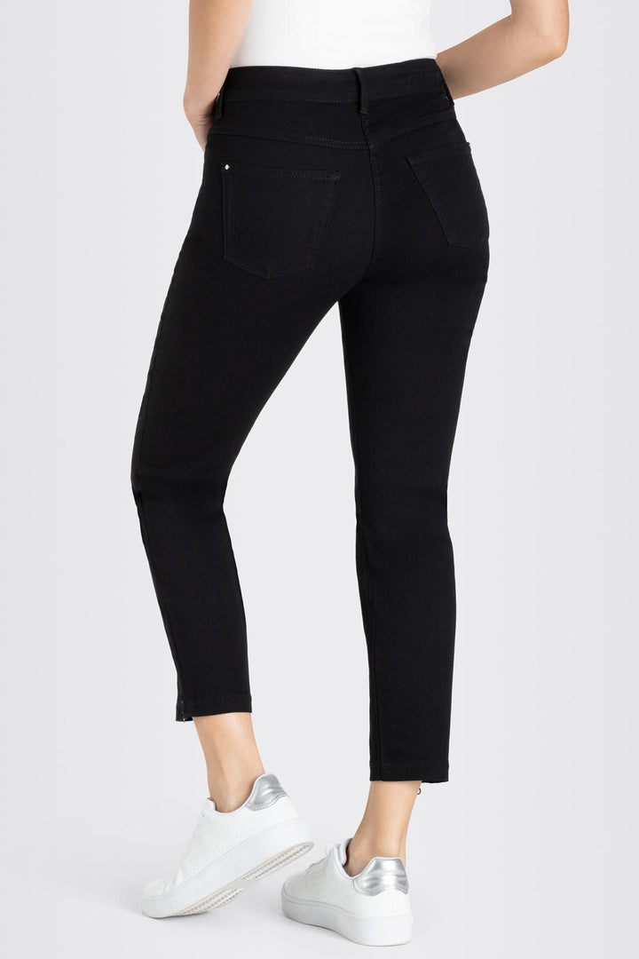 Person wearing black jeans and white sneakers on a white background