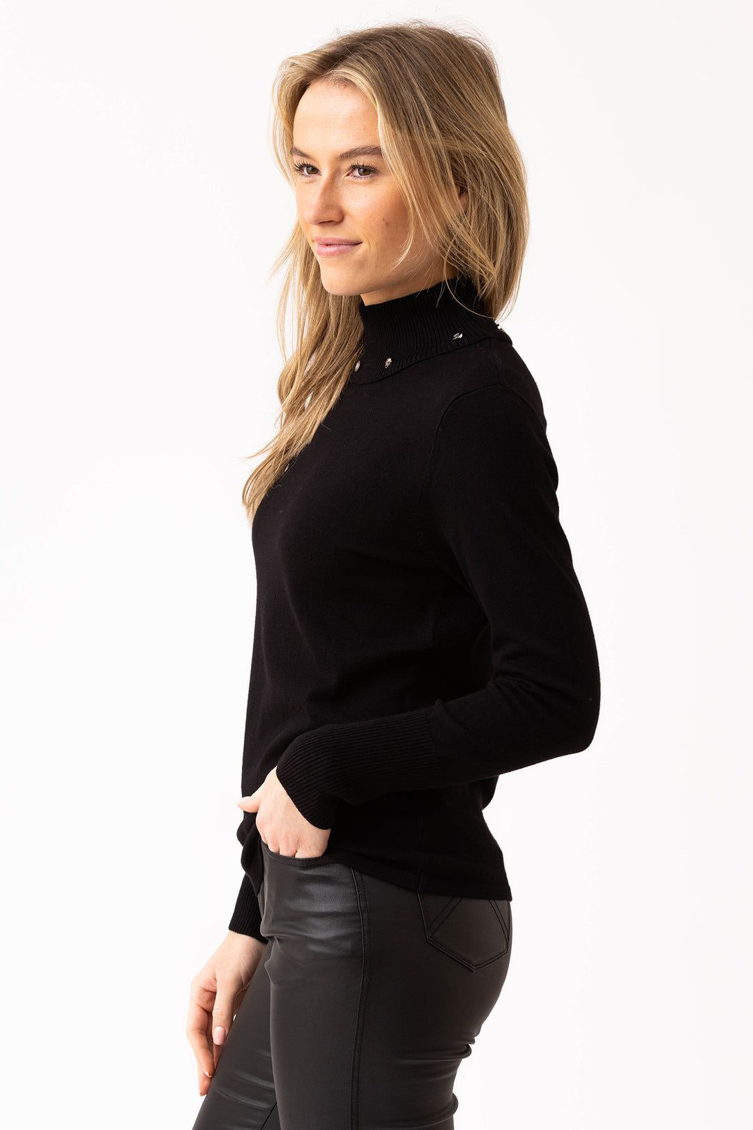 Woman wearing a black turtleneck sweater and leather pants on a white background
