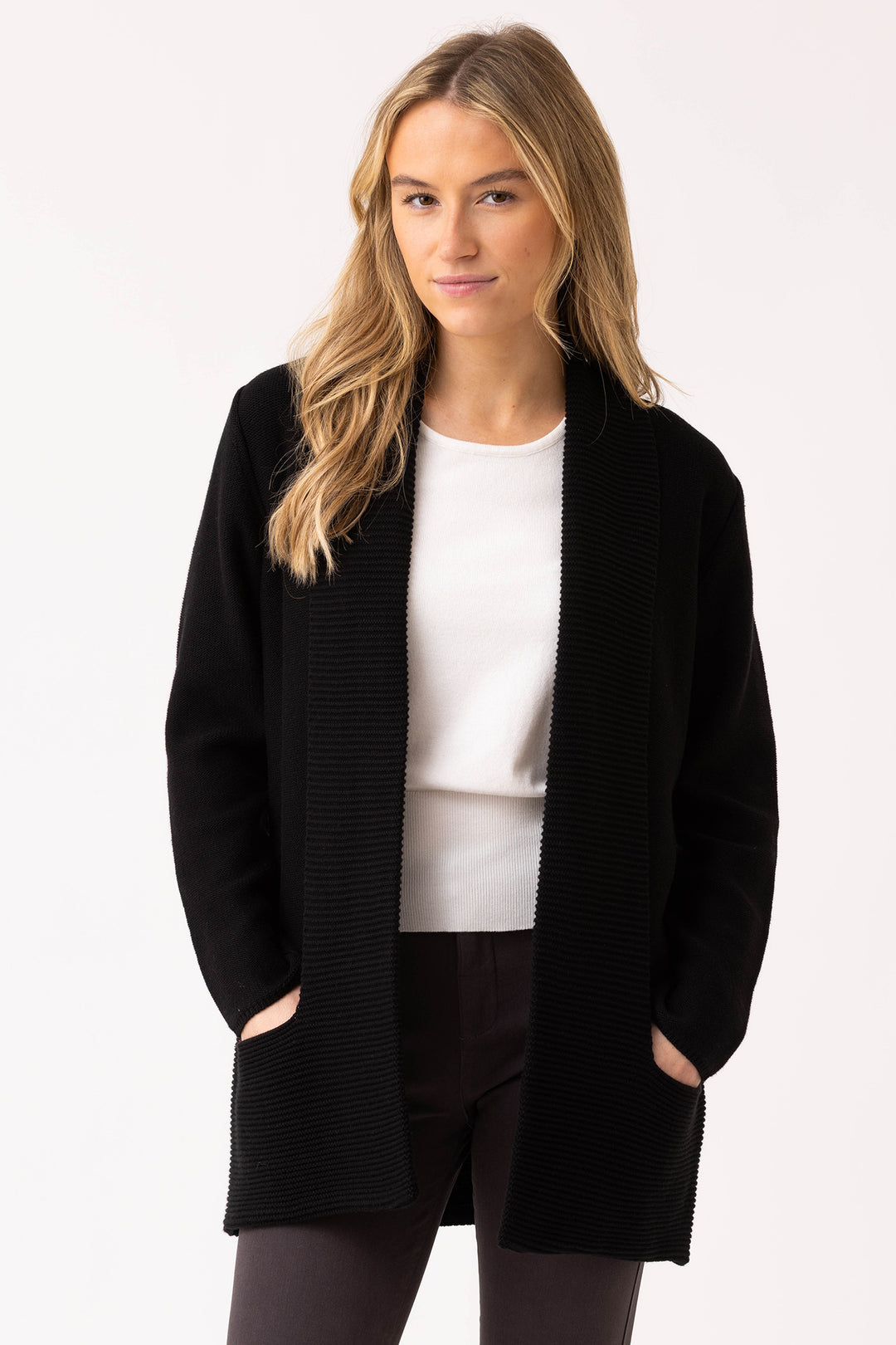 Woman wearing a black cardigan over a white top and black pants on a white background