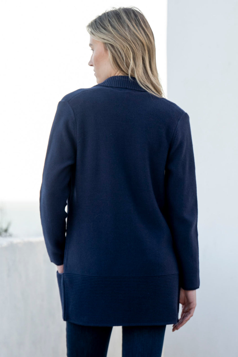 Person wearing a navy blue cardigan against a white background