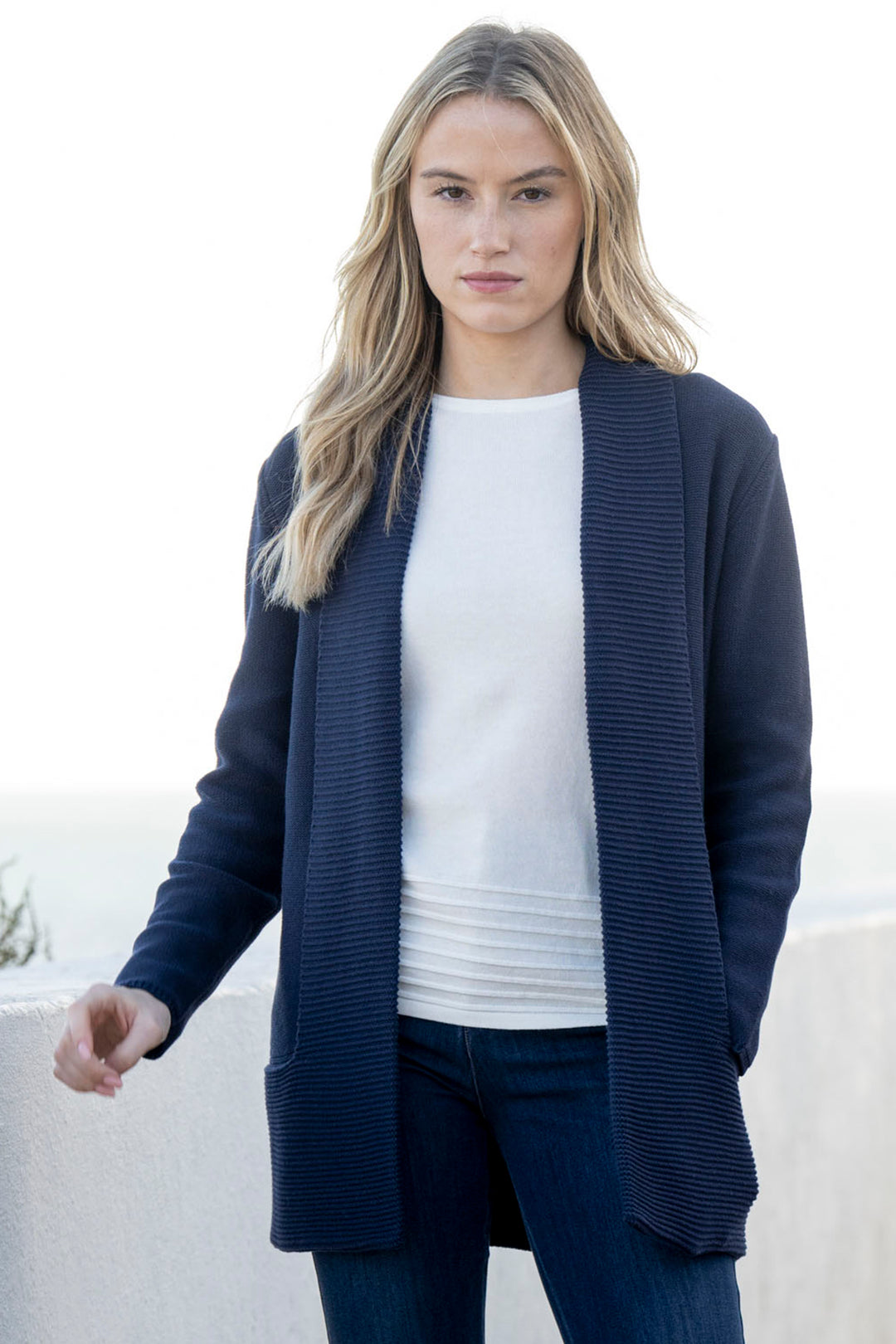 Woman wearing a navy cardigan over a white shirt with a blurred background